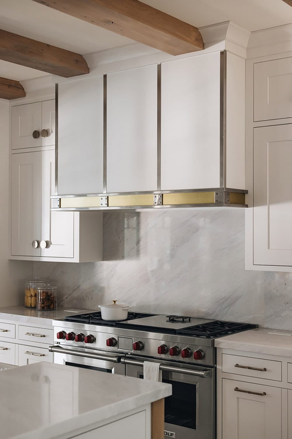 Close-up of range hood with brass trim above stainless gas range