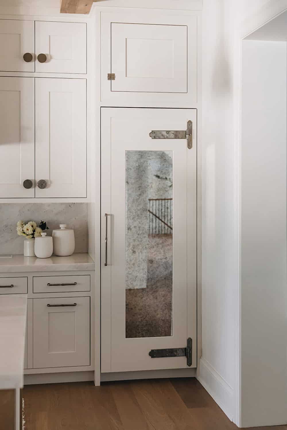 Built-in refrigerator with antiqued mirror panel and iron strap hinges