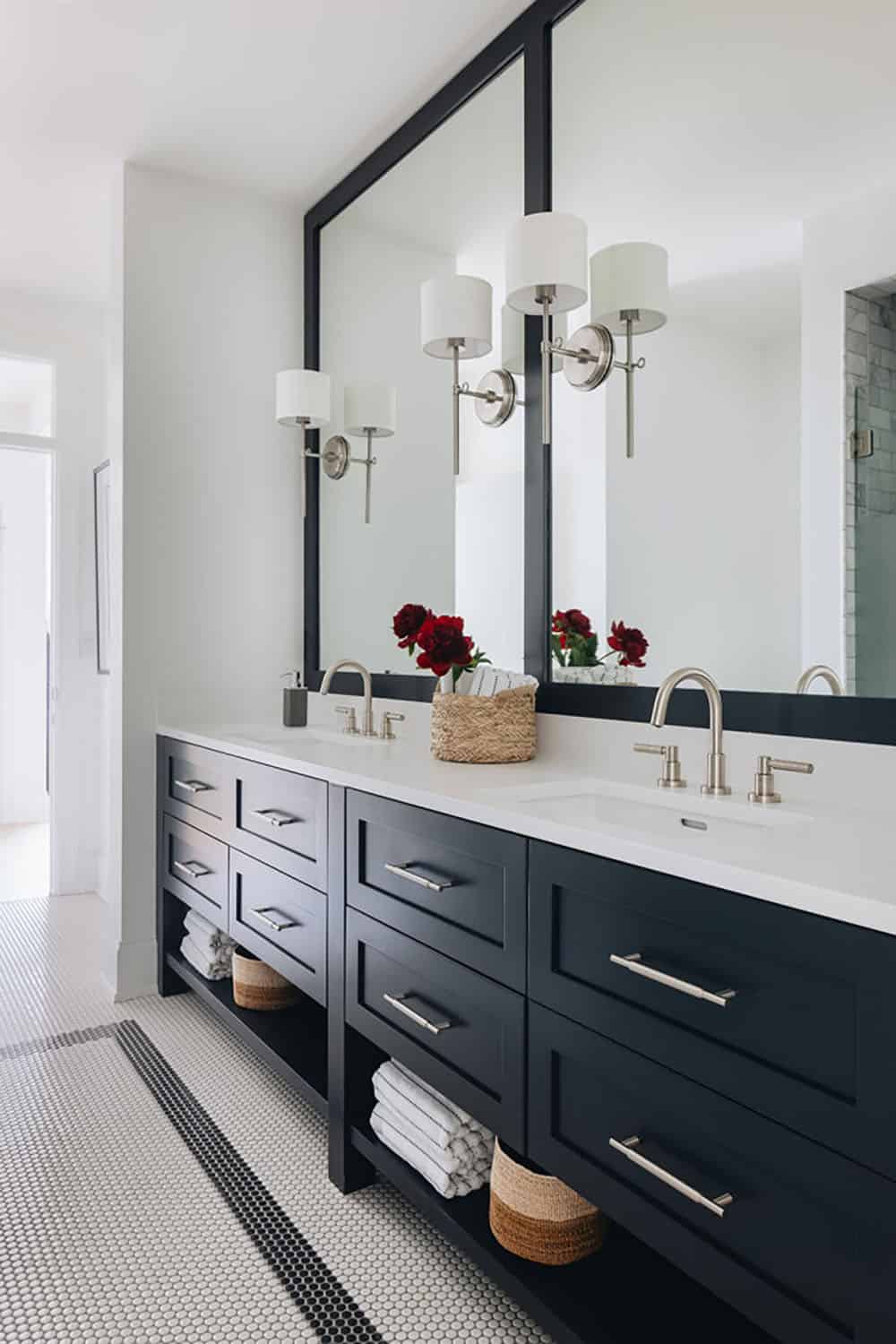 Navy double vanity with black-framed mirrors and penny tile floor