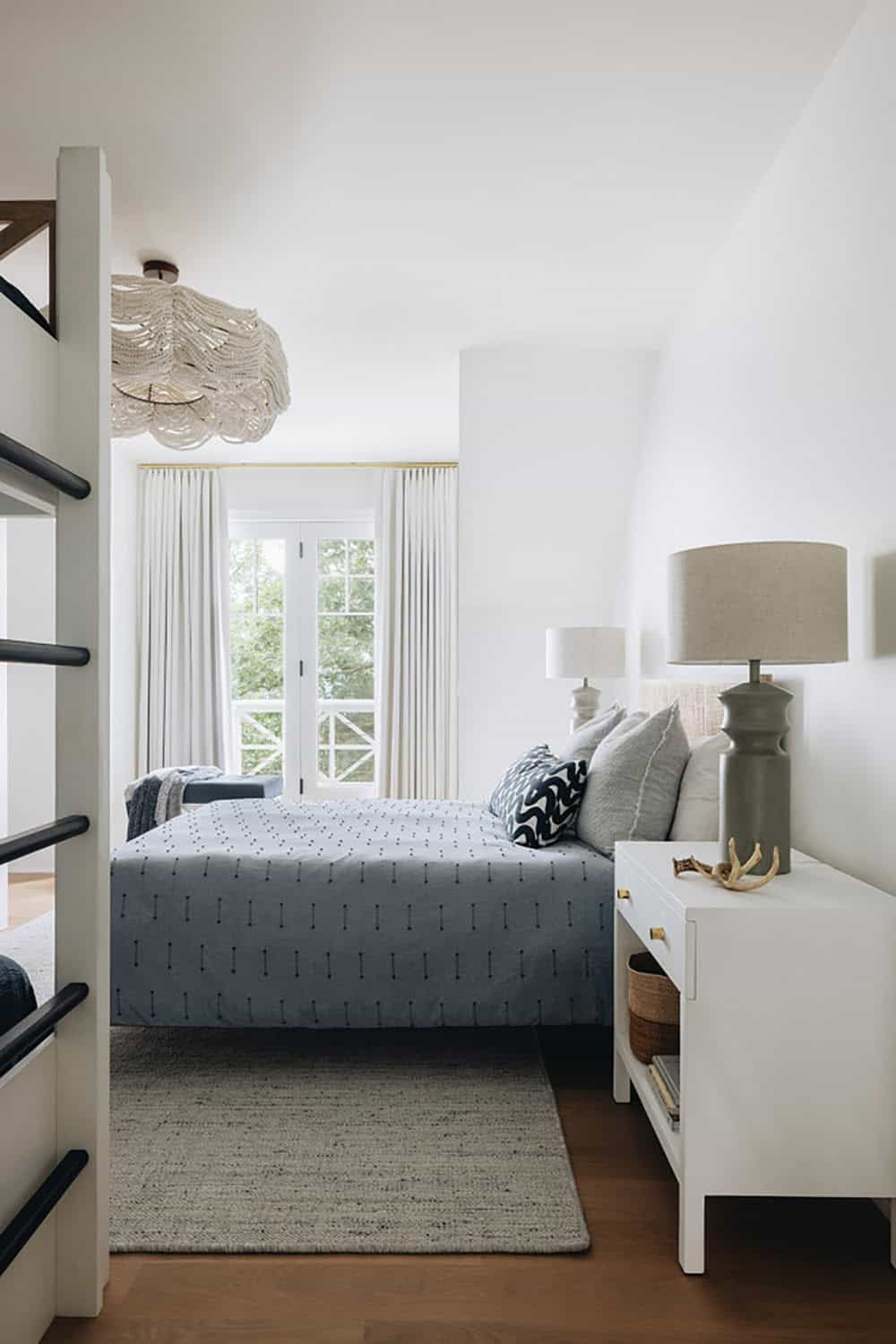 Bedroom with woven bead chandelier, blue coverlet, and bunk bed ladder