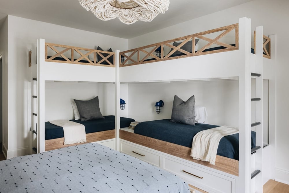 Built-in bunk beds with navy bedding beneath woven bead chandelier