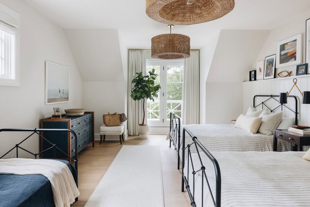 Twin bedroom with black iron beds and woven drum pendant lights