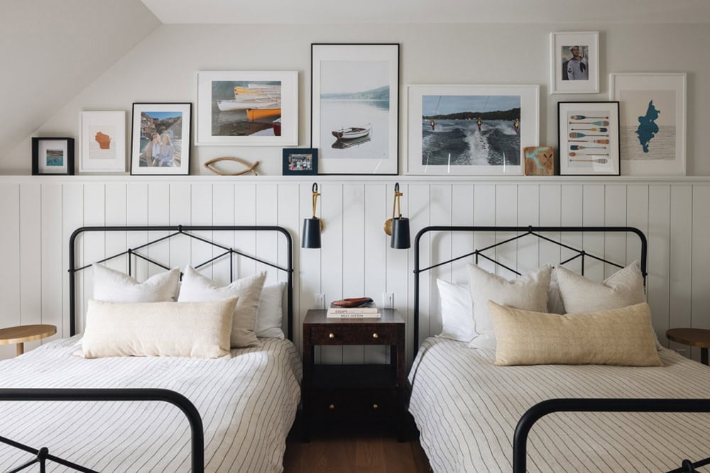 Twin beds with striped bedding under a boating-themed gallery wall
