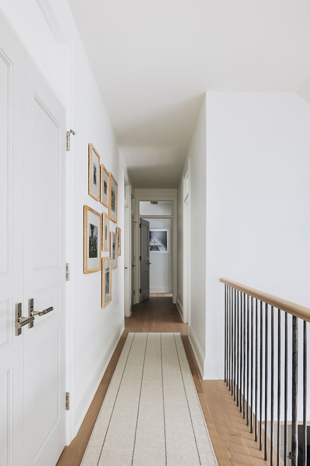 Upstairs hallway with gold-framed gallery wall and striped runner rug