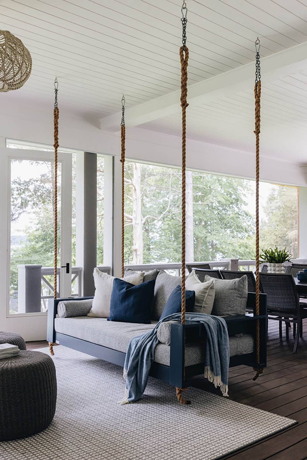 Hanging porch swing bed with navy pillows overlooking dining area and lake