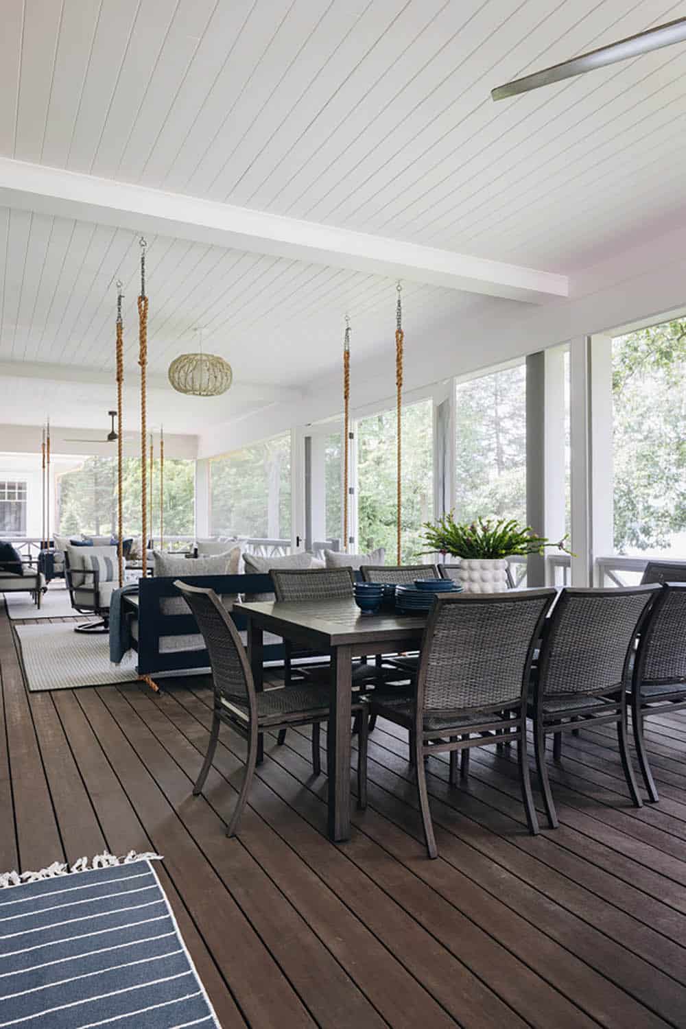 Long screened porch with outdoor dining table and hanging swing beyond