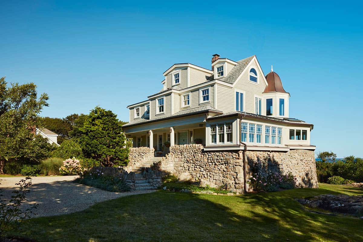 Shingle-style beachfront home with stone foundation and turret entry