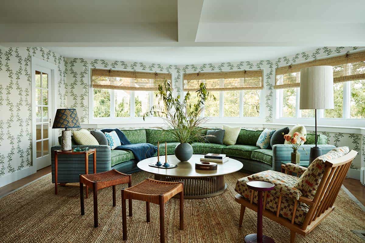 Sunroom with green sectional sofa and botanical print wallpaper