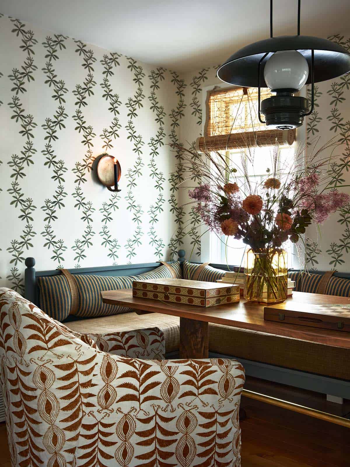 Breakfast nook with leaf-print wallpaper and rust floral armchair