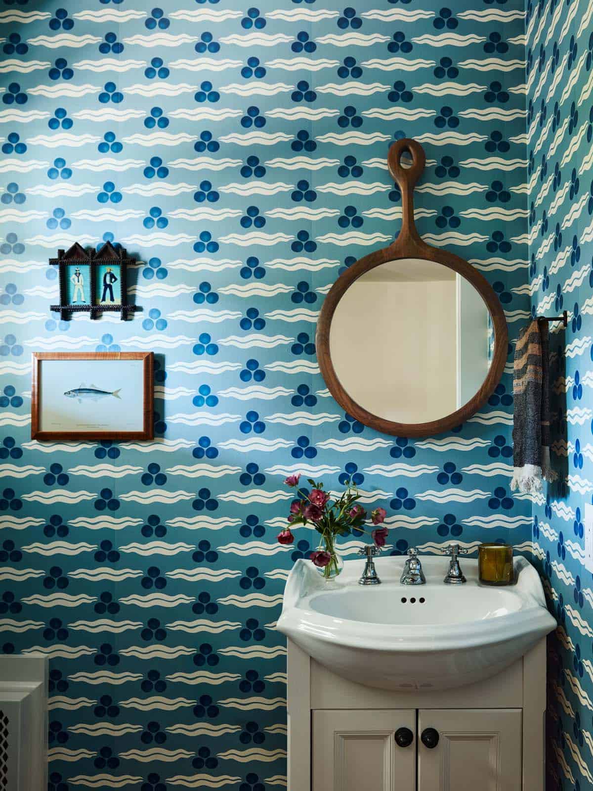 Powder room with blue wave-print wallpaper and wood mirror