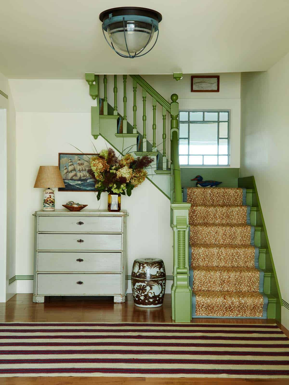 Entryway staircase with green trim and woven stair runner
