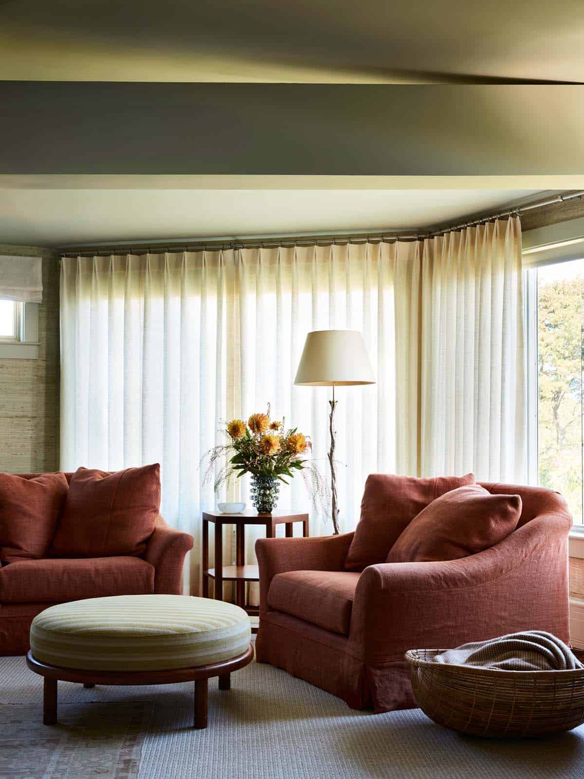 Primary bedroom sitting area with rust armchairs and sheer curtains