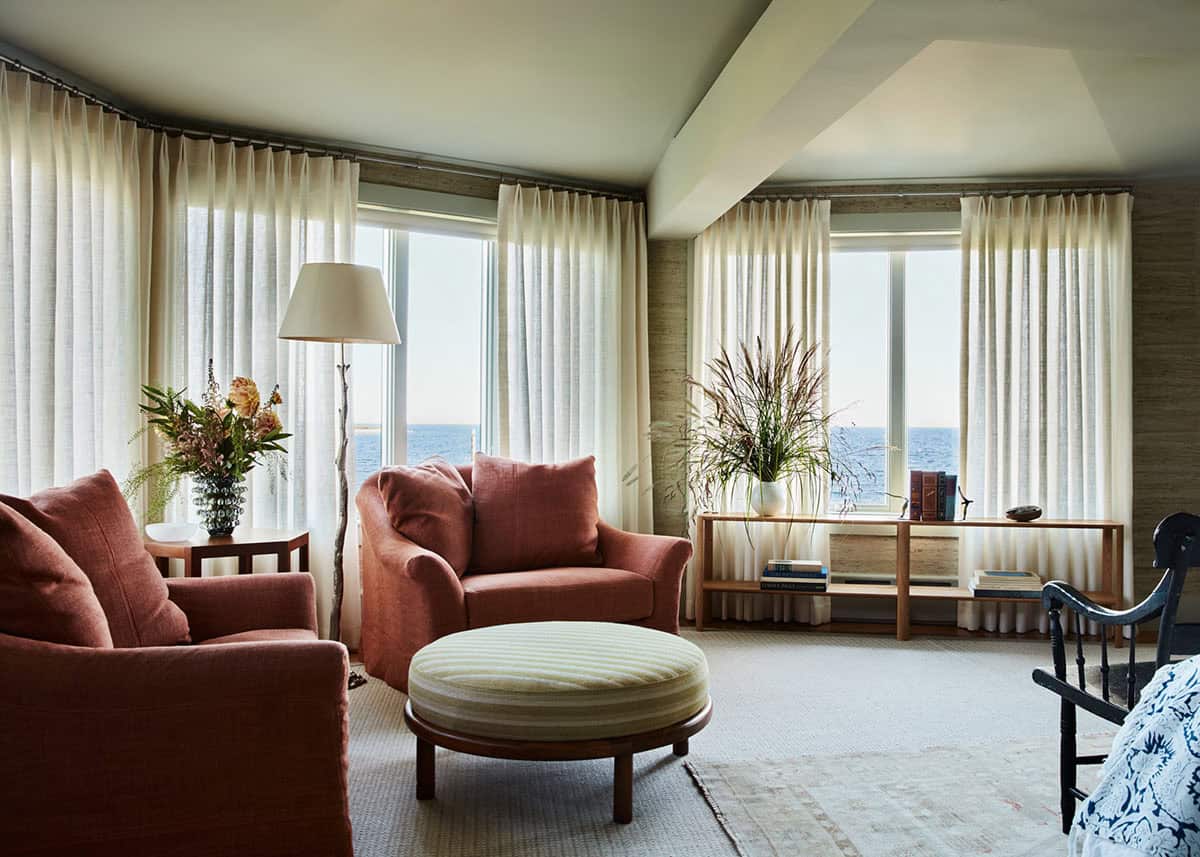 Ocean-view sitting room with rust armchairs and sheer drapery