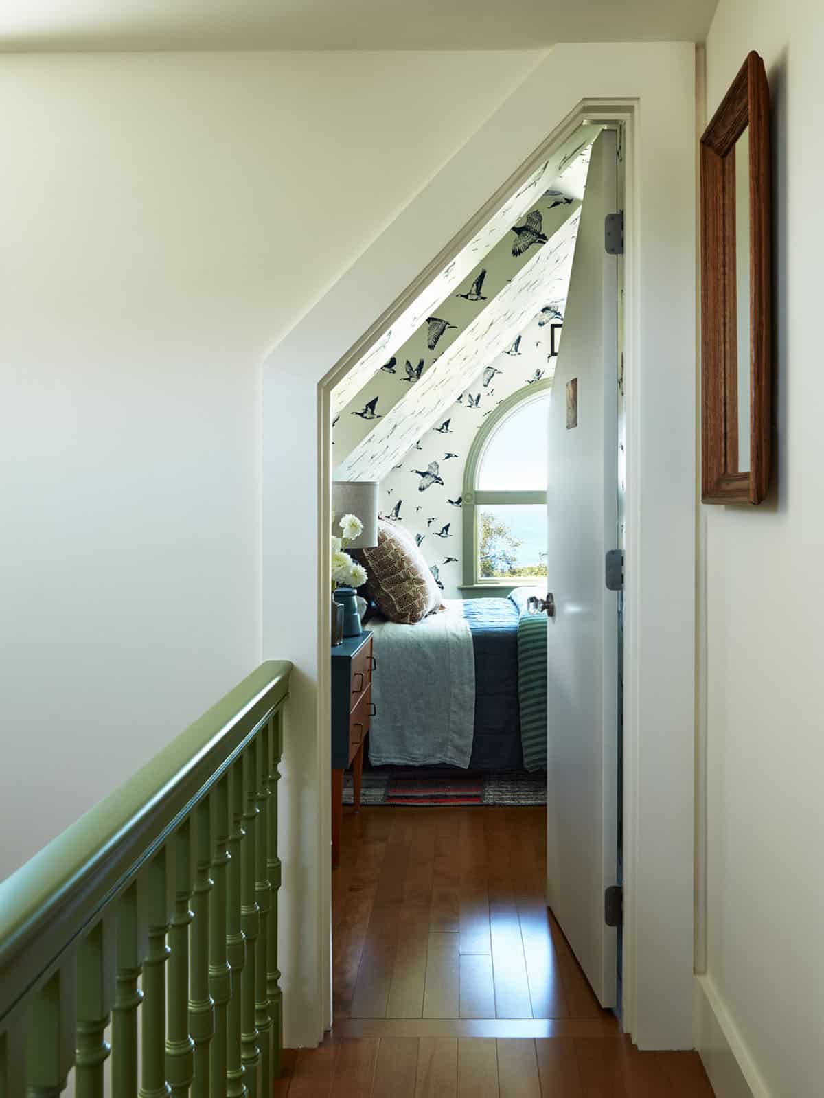 Hallway view into bird-print wallpapered guest bedroom
