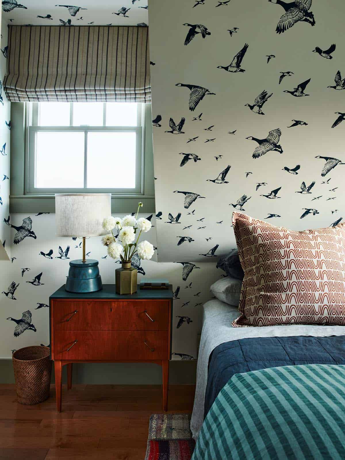 Guest bedroom nightstand detail with bird-print wallpaper