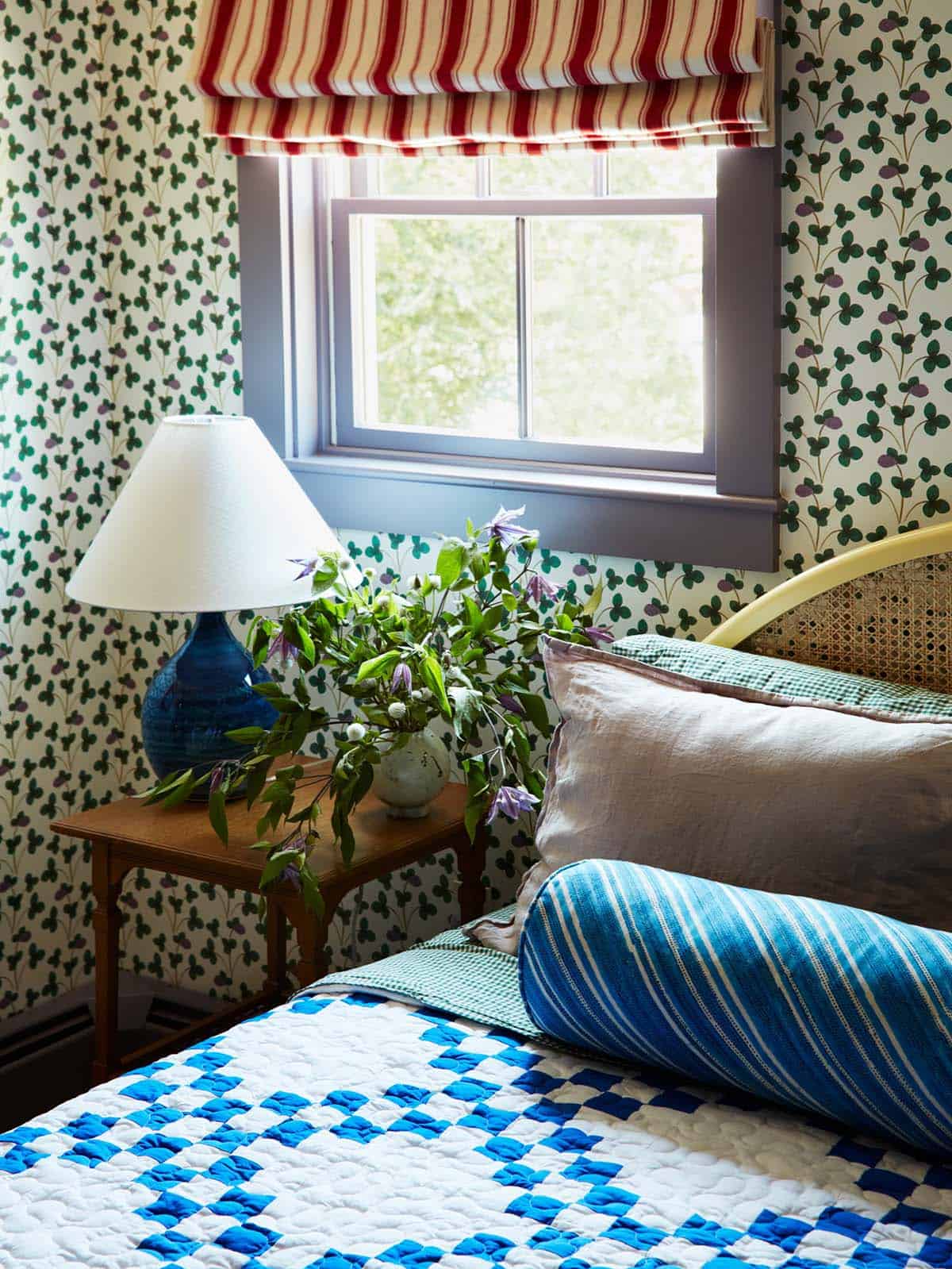 Nightstand detail with clover wallpaper and striped bolster pillow
