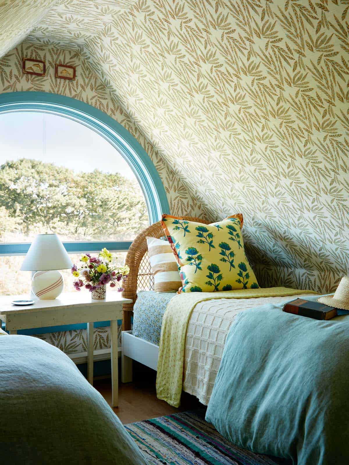 Twin bed detail with leaf wallpaper and floral throw pillow