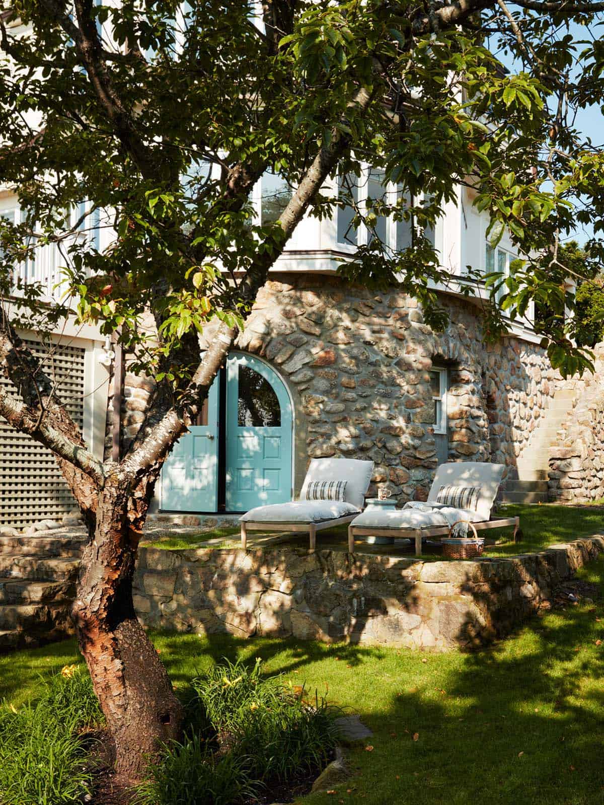Stone garden facade with turquoise arched door and loungers