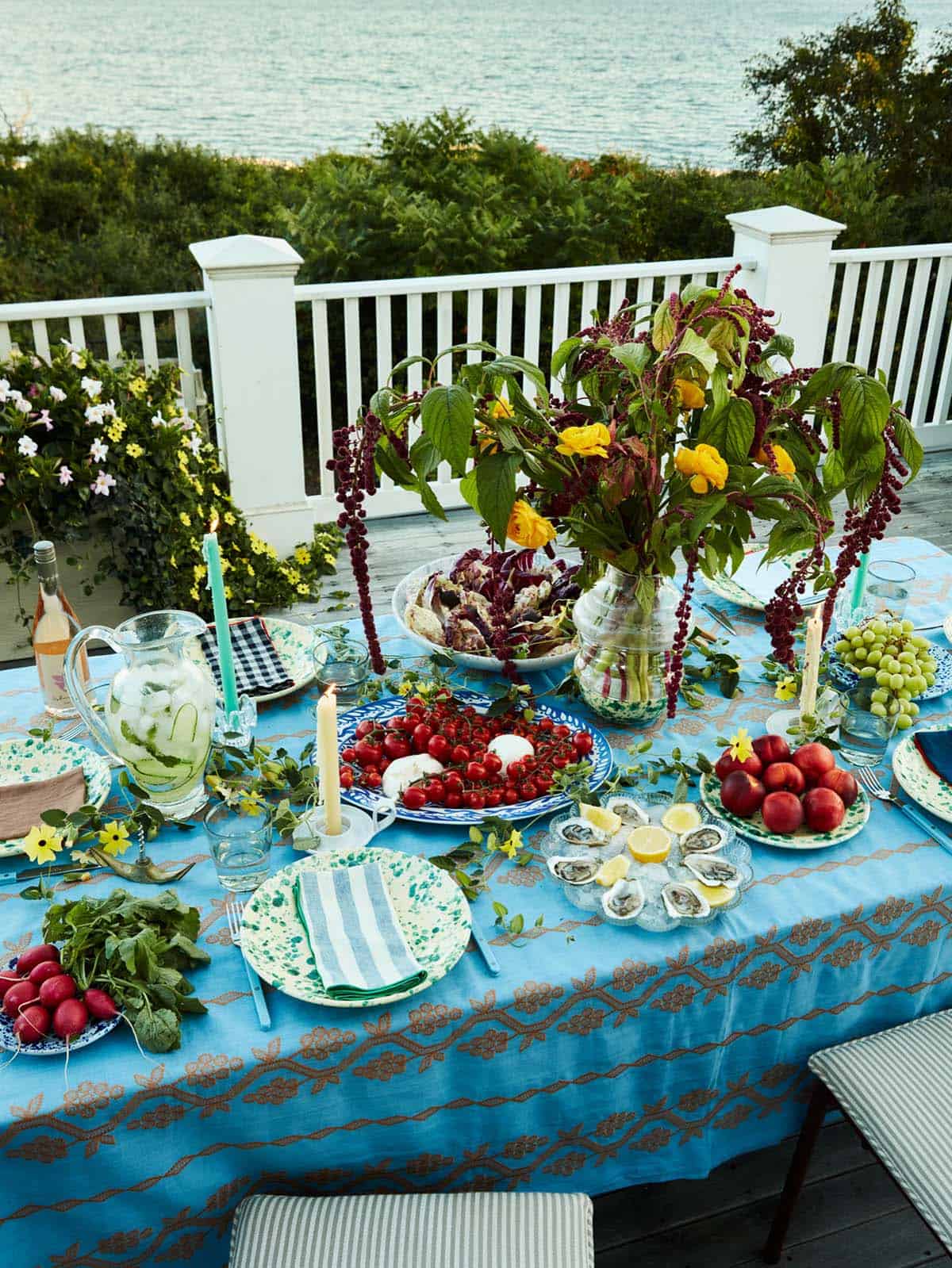 Outdoor table set with tomatoes, oysters, and amaranth centerpiece