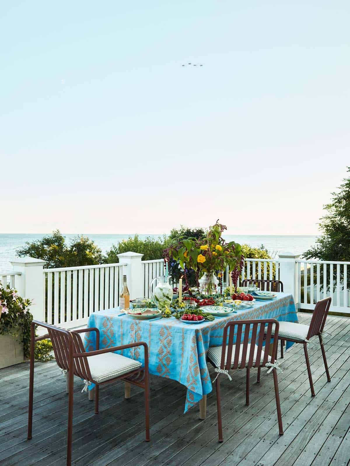 Table set with blue floral tablecloth on a deck with an ocean view