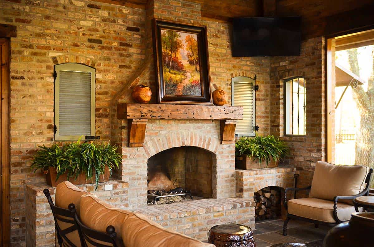 Rustic brick fireplace with wood mantel on a covered patio