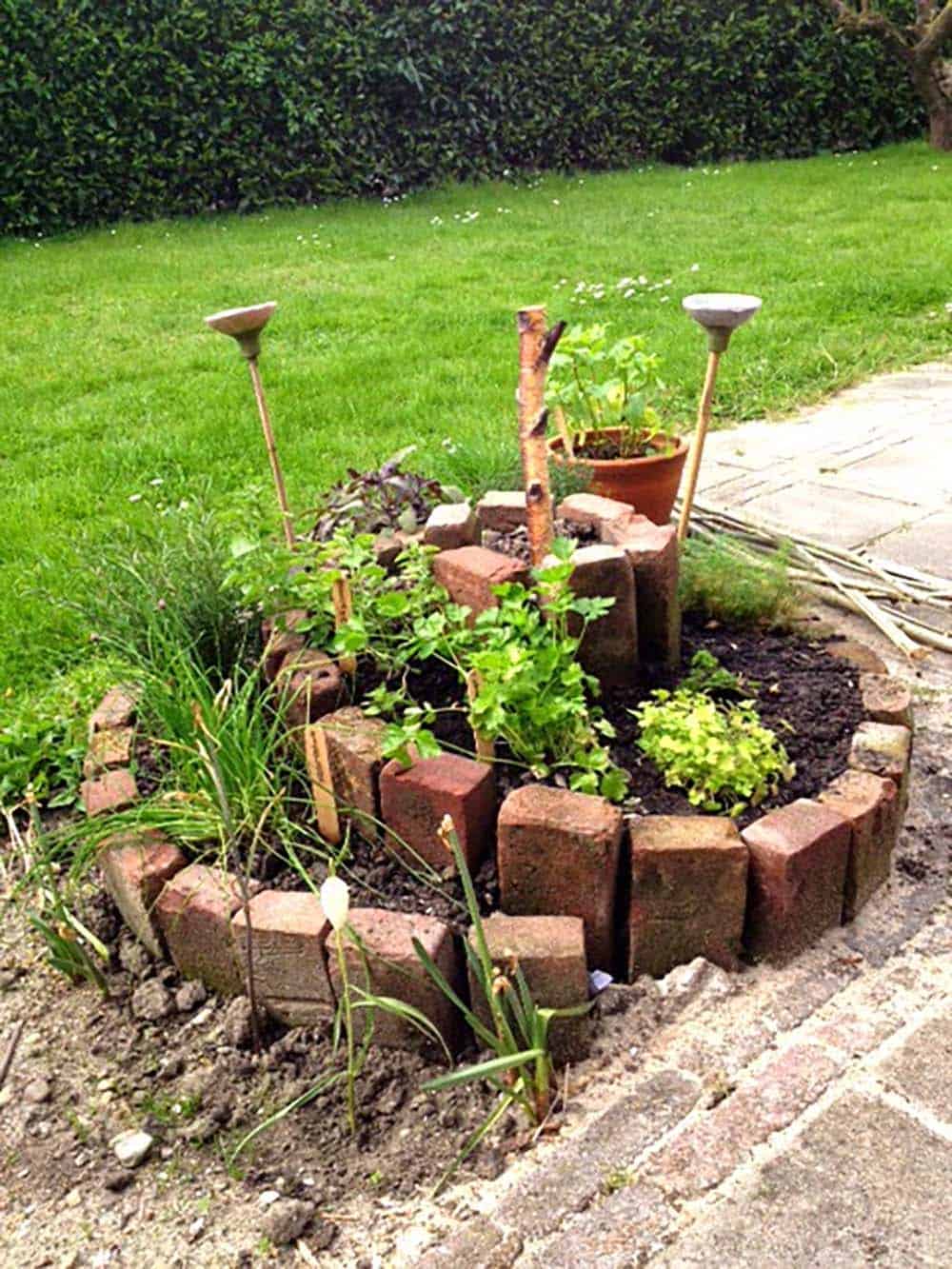 Reclaimed bricks stacked on end in a rising spiral to form a small spice garden filled with herbs