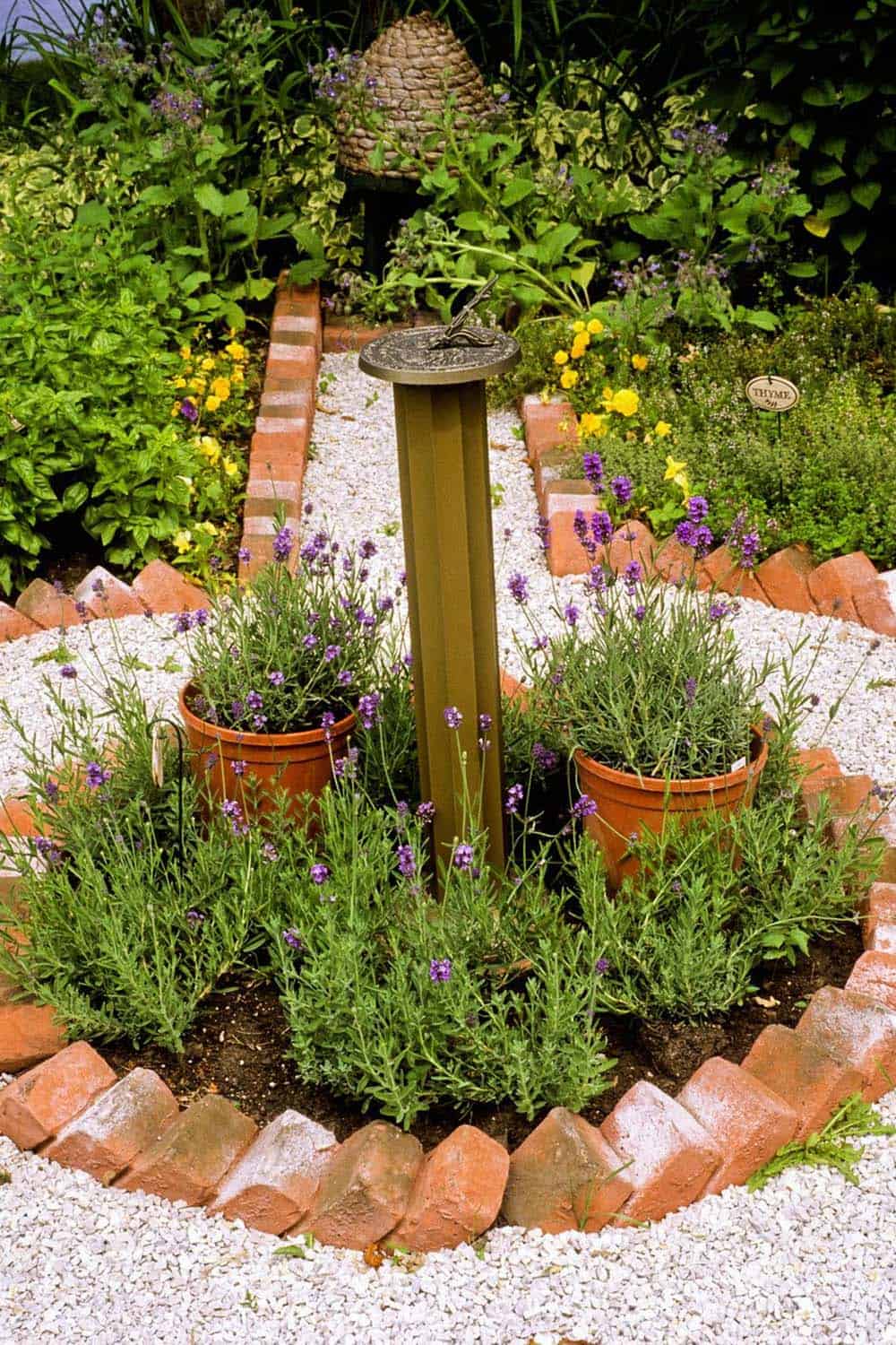 A sundial rises from a circular garden bed edged in brick and surrounded by lavender plantings