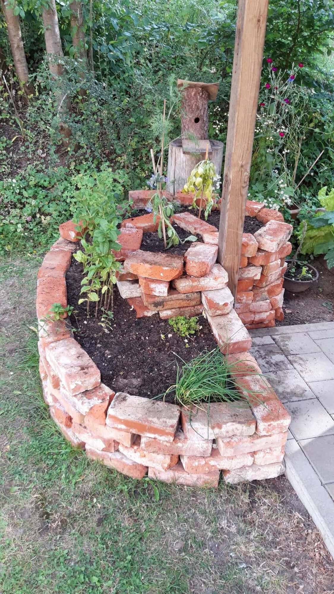 Circular raised garden bed built from reclaimed brick with an internal partition