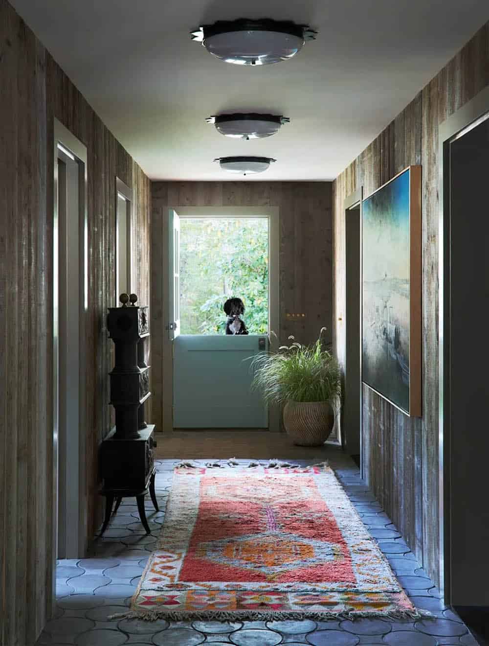 Rustic hallway with kilim runner and dog peeking through Dutch door