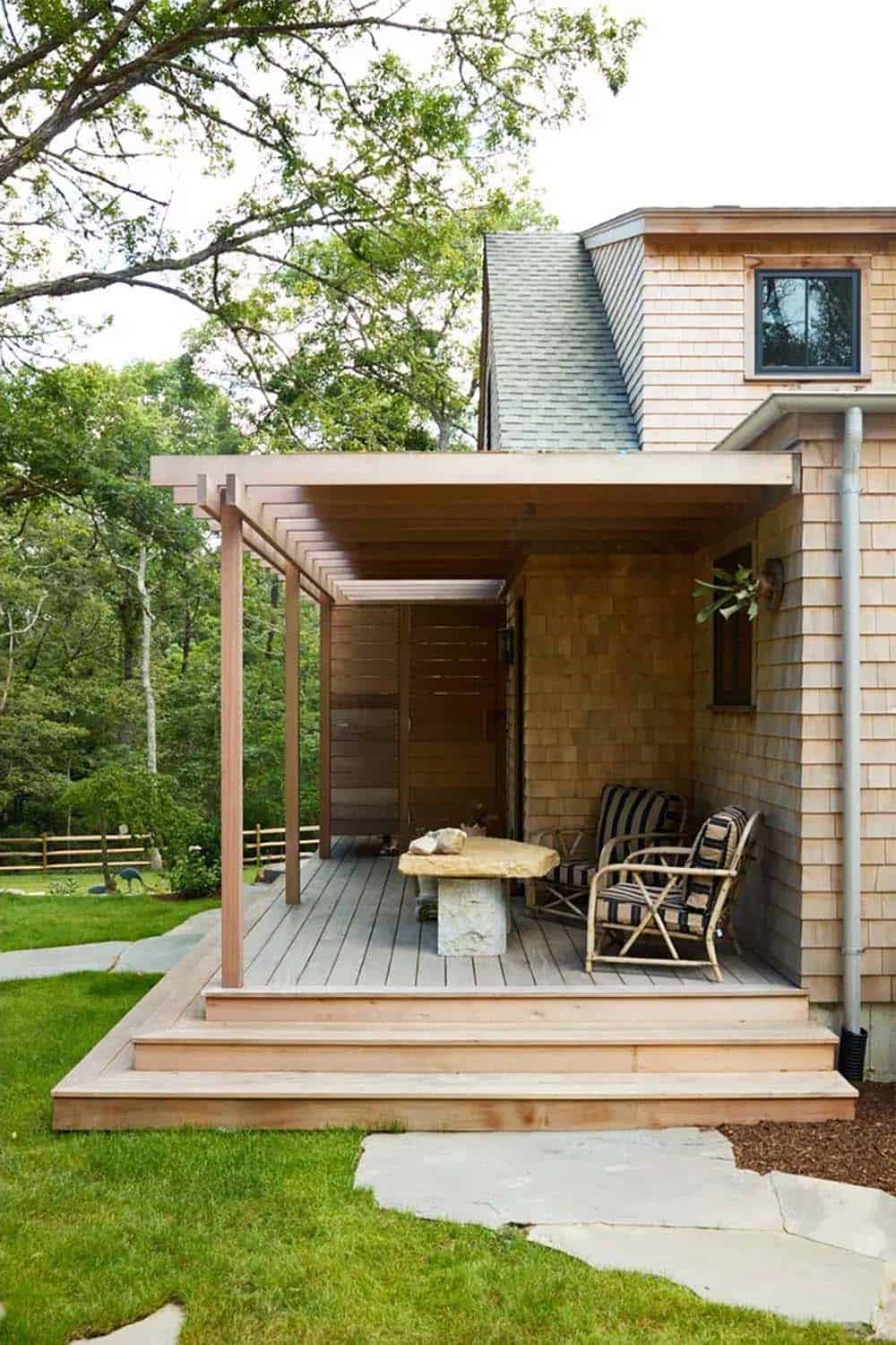 Cedar shingle home addition with flat pergola roof and wicker chairs