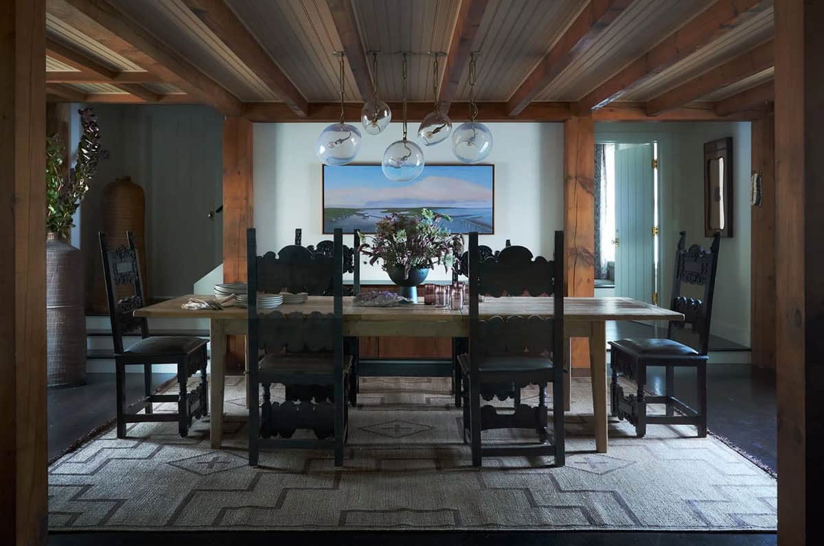 Dining room with globe pendants, carved chairs, and coastal artwork