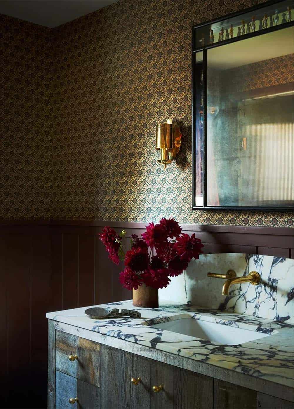 Powder room vanity with marble countertop and patterned wallpaper