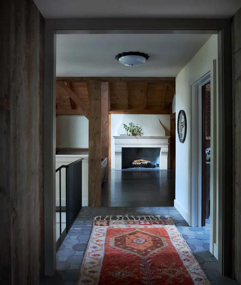 Hallway view toward stone fireplace with kilim runner on tile floor