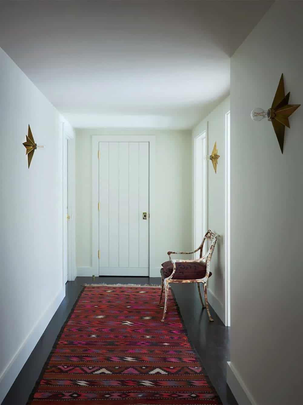 Hallway with kilim runner, star sconces, and vintage iron chair