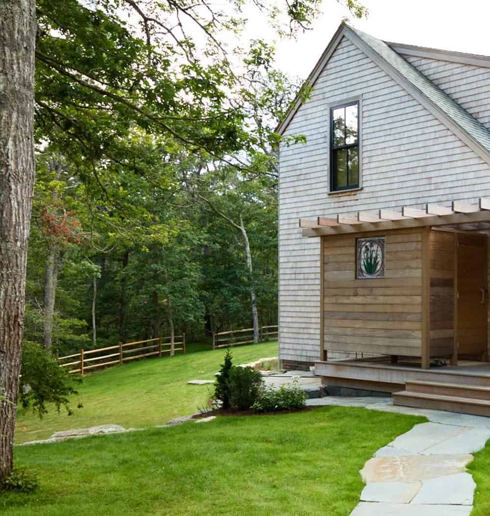 Shingle-style home exterior with pergola detail and split-rail fence