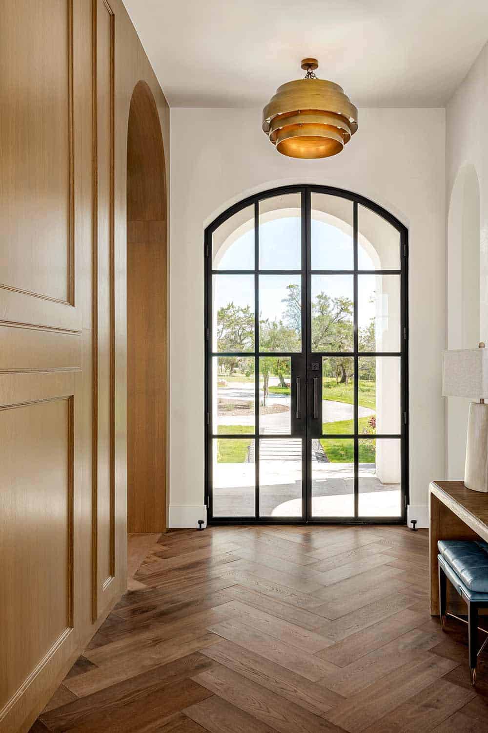 Herringbone wood floor entryway with brass drum pendant light
