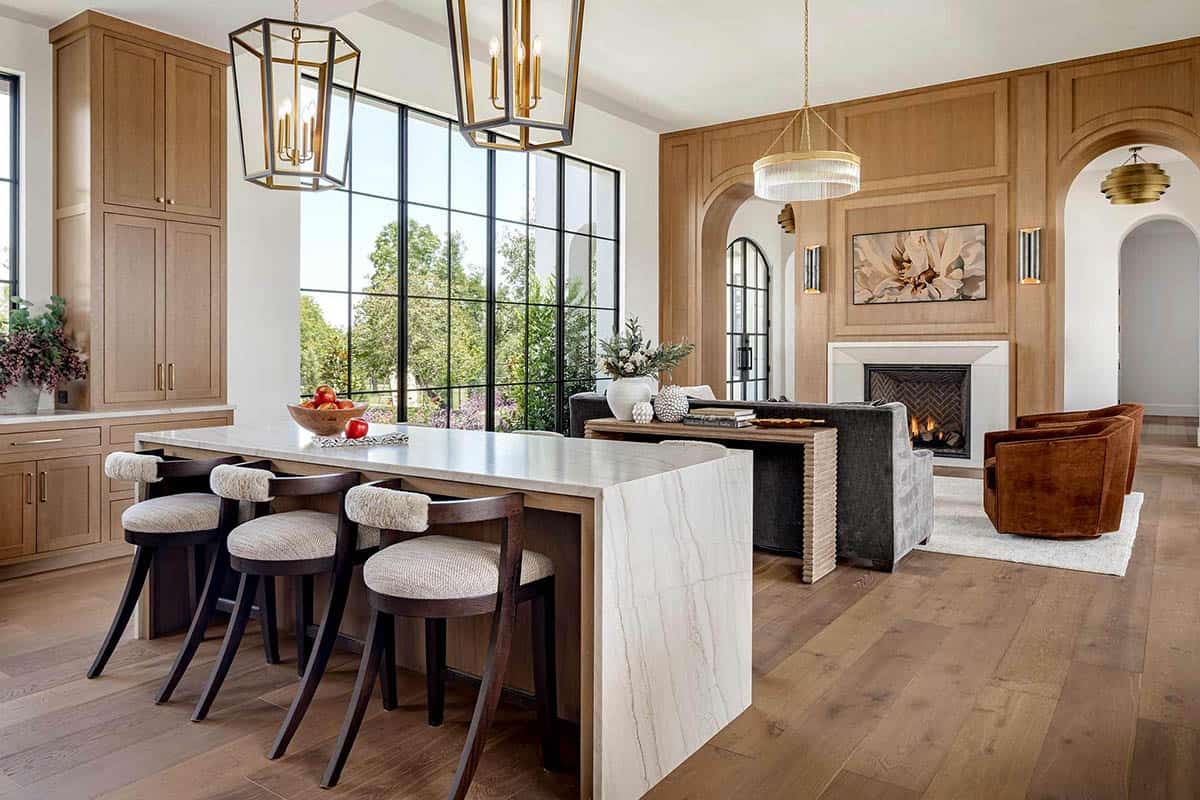Kitchen island facing living room with brass lantern pendants