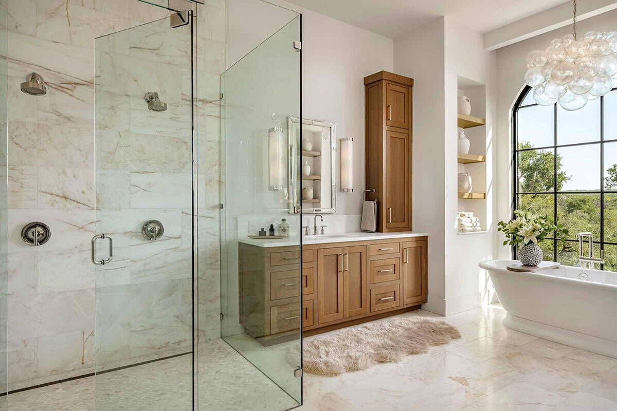 Primary bathroom with marble shower and wood vanity cabinetry