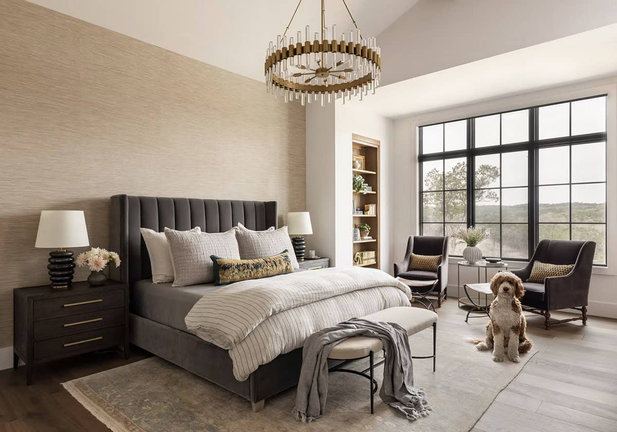 Bedroom with tufted headboard, brass chandelier, and dog on rug