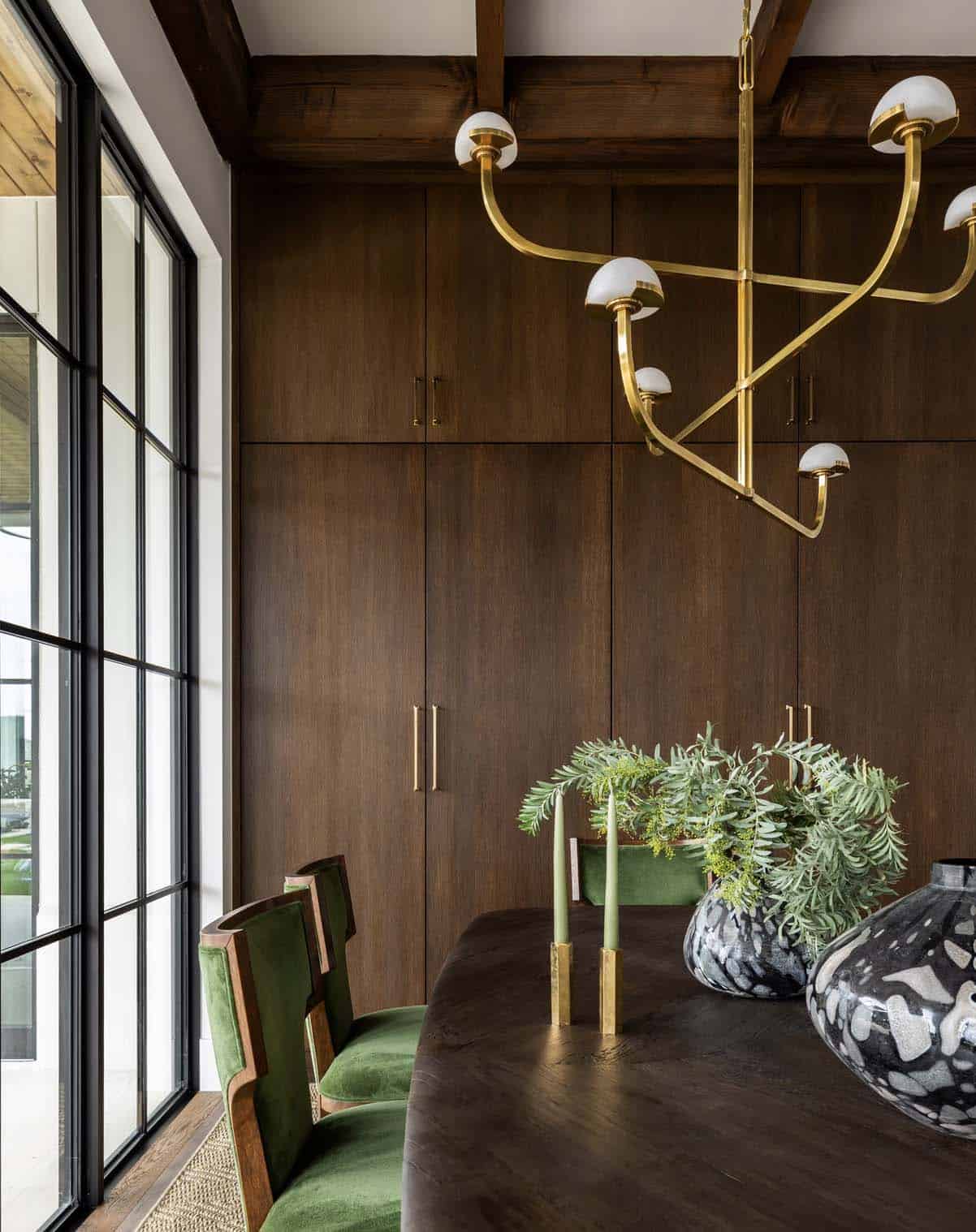 Dining table detail with brass chandelier and dark wood cabinetry