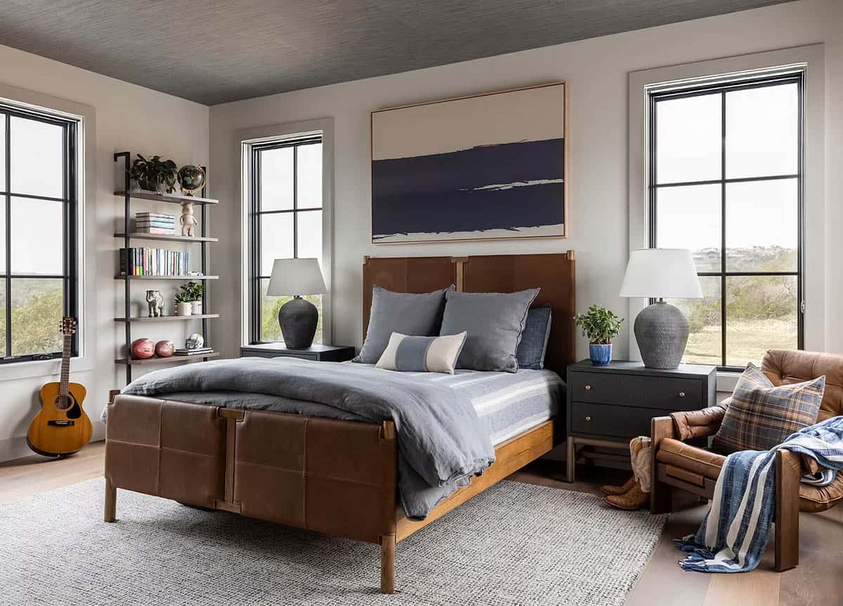 Bedroom with leather bed frame, guitar, and navy landscape art