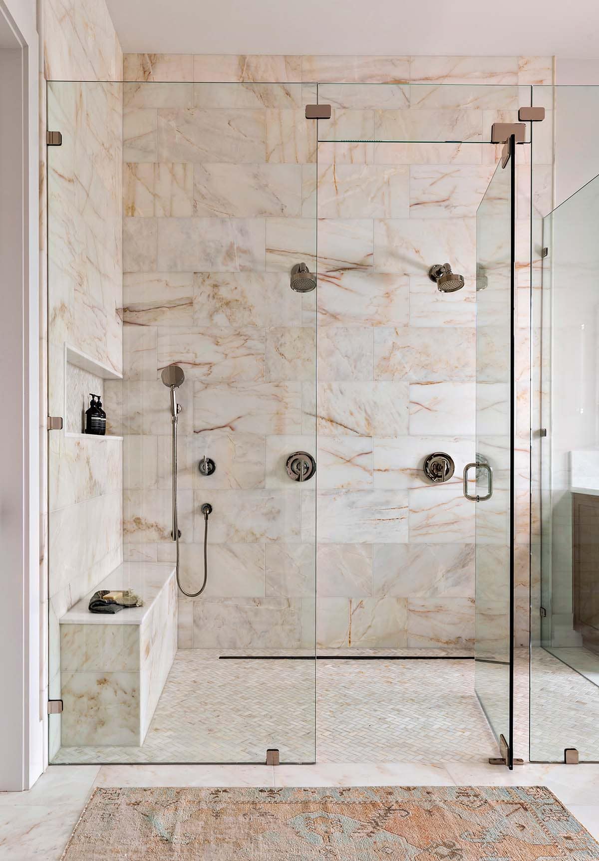 Marble walk-in shower with dual rainfall showerheads and bench