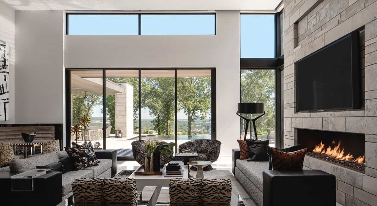 Living room with stone fireplace wall and floor-to-ceiling glass doors