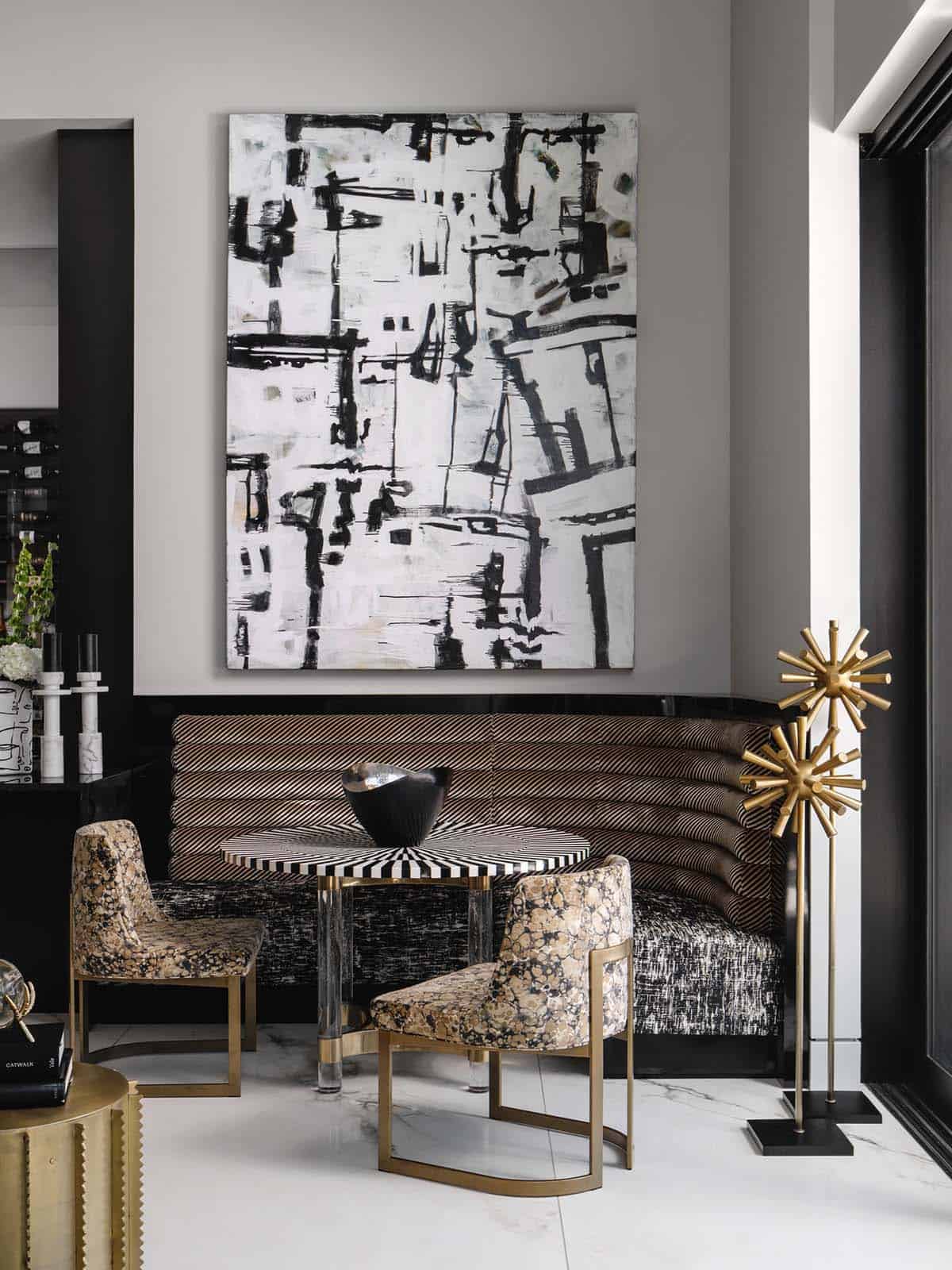 Banquette seating beneath a bold abstract painting and brass starburst sculptures