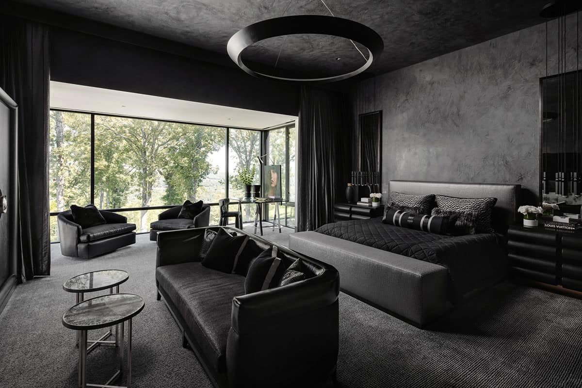 All-black primary bedroom with leather seating and panoramic window views