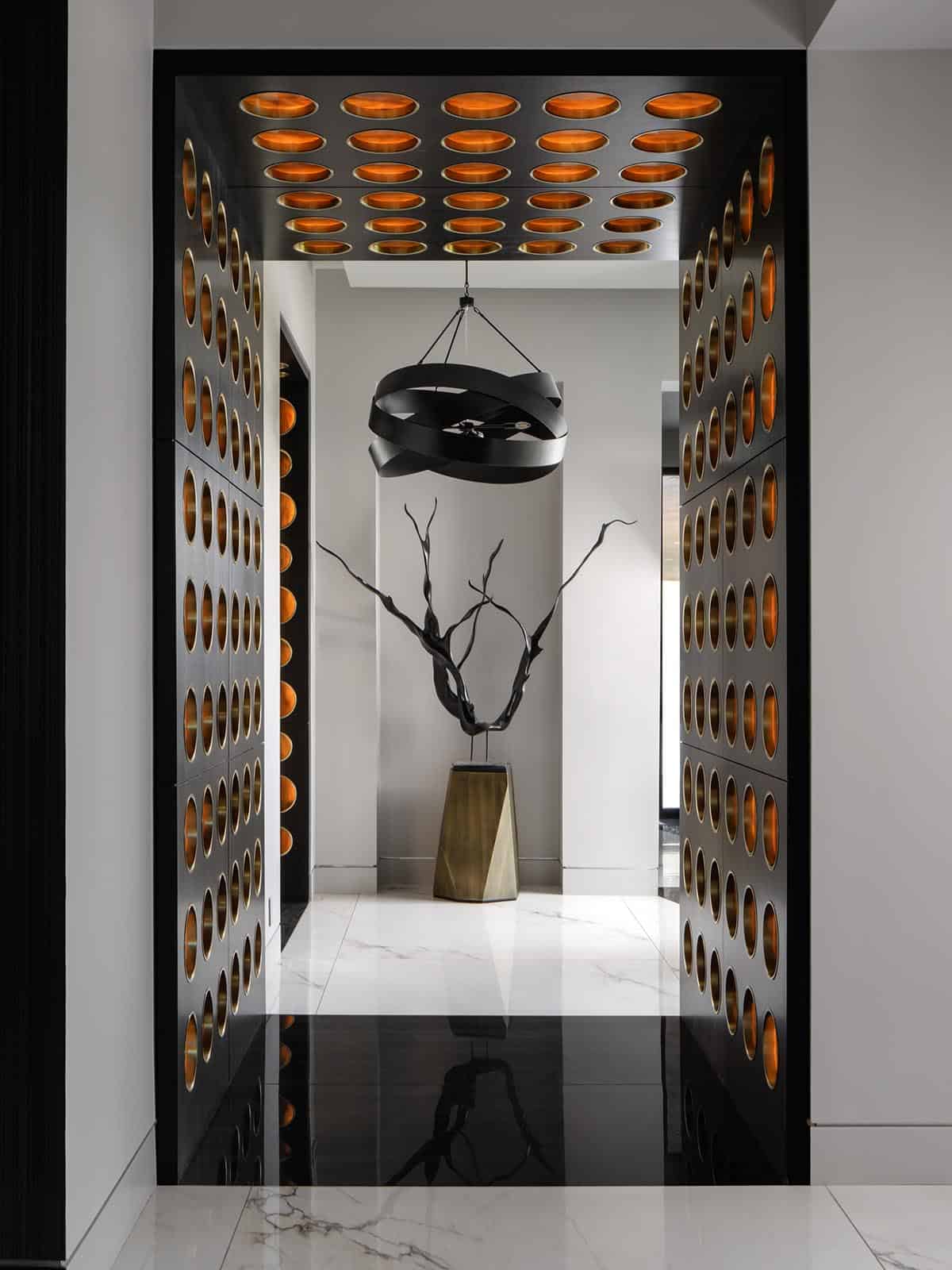 Black cabinet hallway with lit orbs leading to a sculptural entry vignette