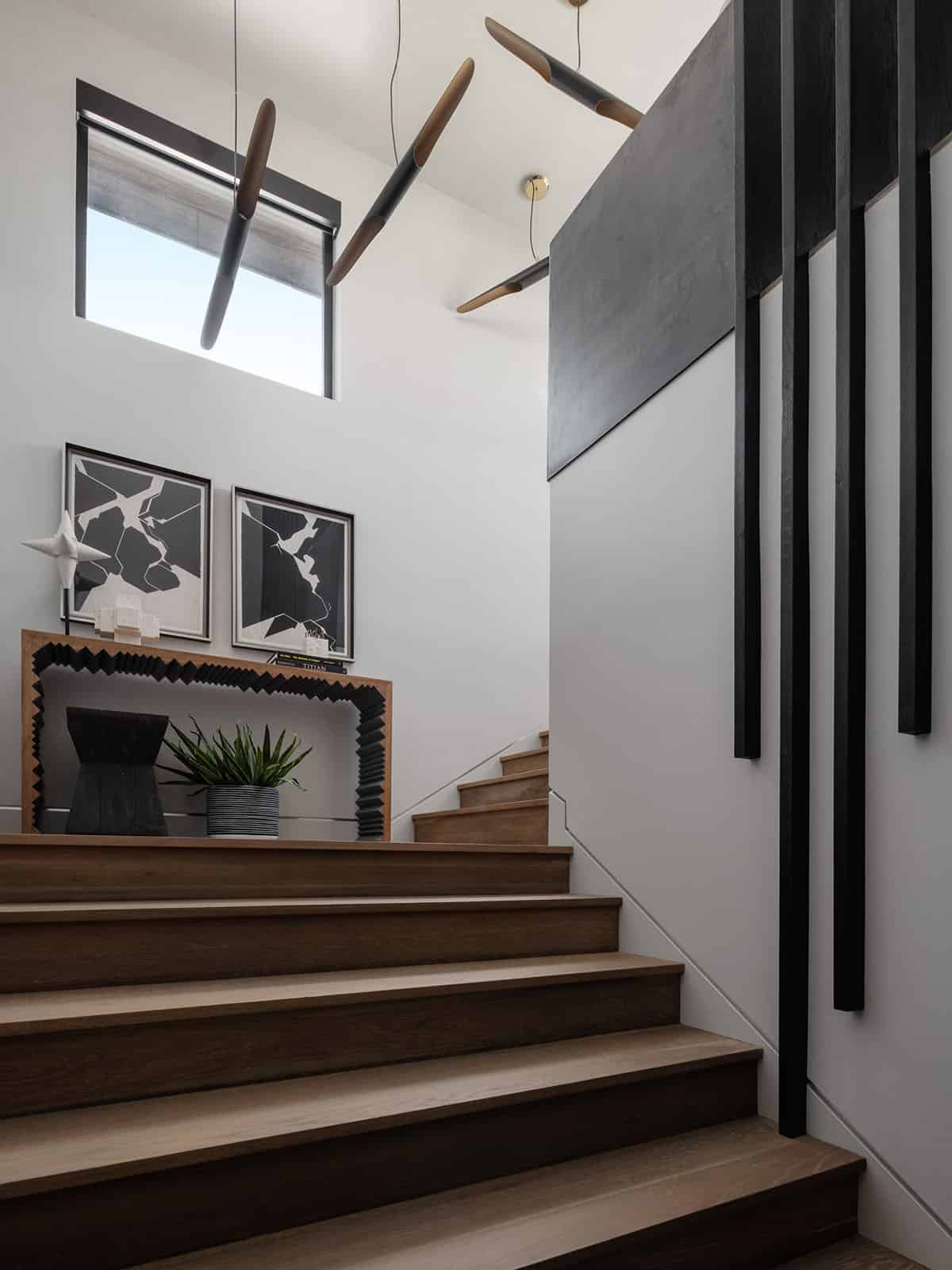 Staircase landing with wood console and sculptural black pendant lights