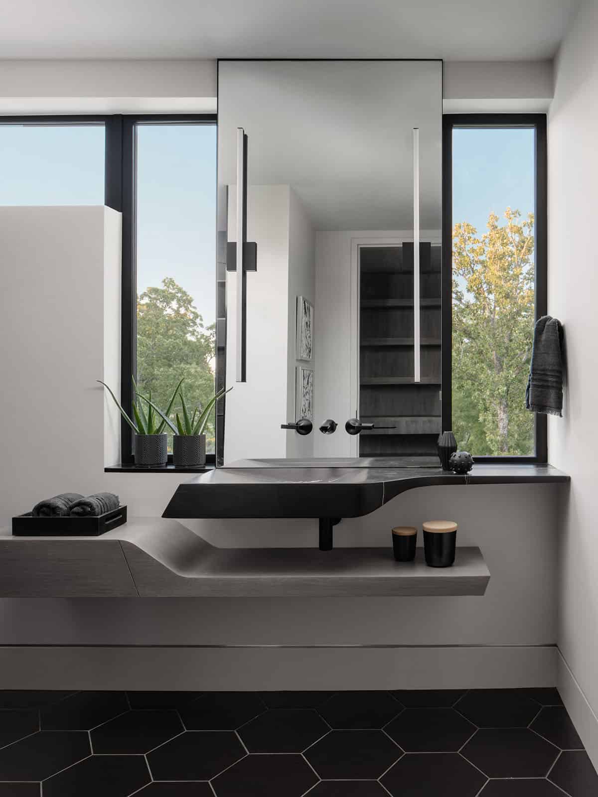 Sculptural black stone vanity sink set beneath a floor-to-ceiling window