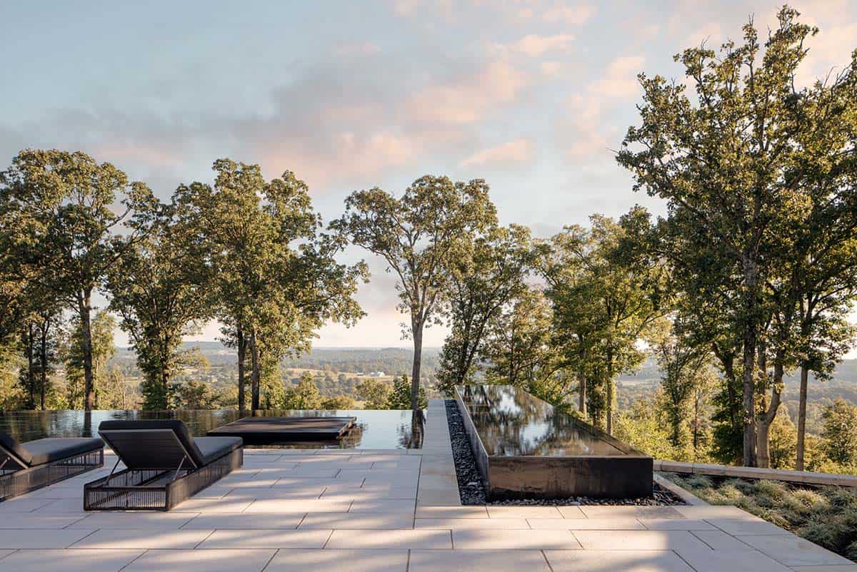 Twilight view of infinity pool deck with black steel water feature
