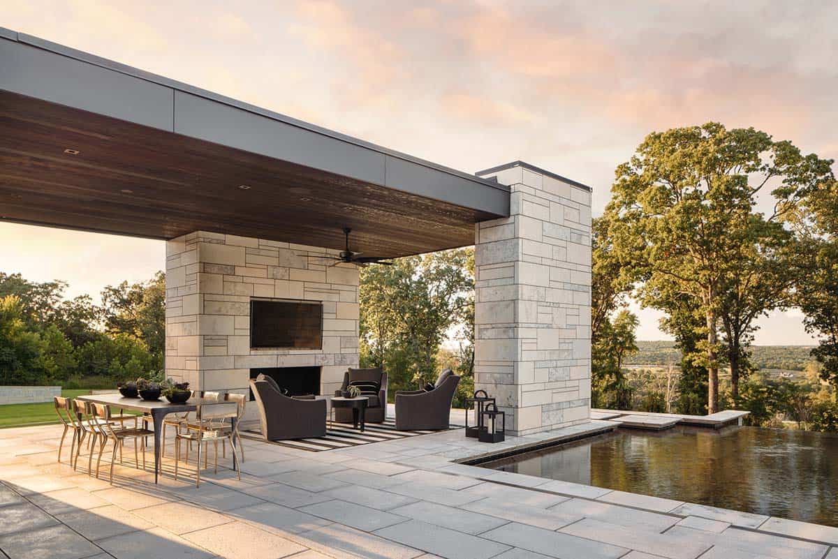Outdoor living pavilion at dusk with dining table and pool views